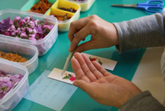 ピンセットを上手く利用し、手際良く作成されていく「押し花しおり」。机の上には、しおりをもらって感動されたお客様からのコメントが。